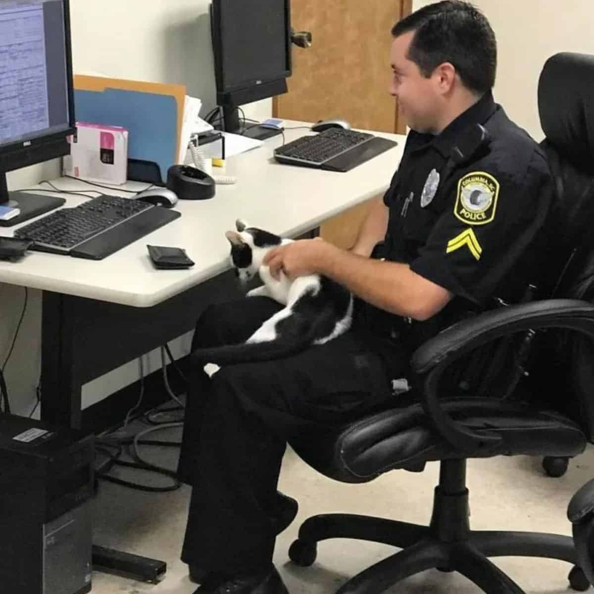 a cat on the lap of a policeman sitting in an armchair