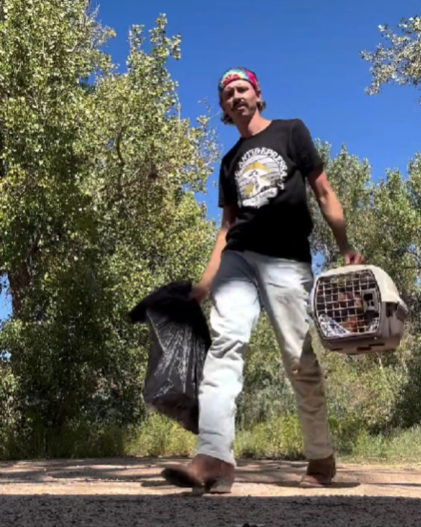 man carrying trash bag and kennel