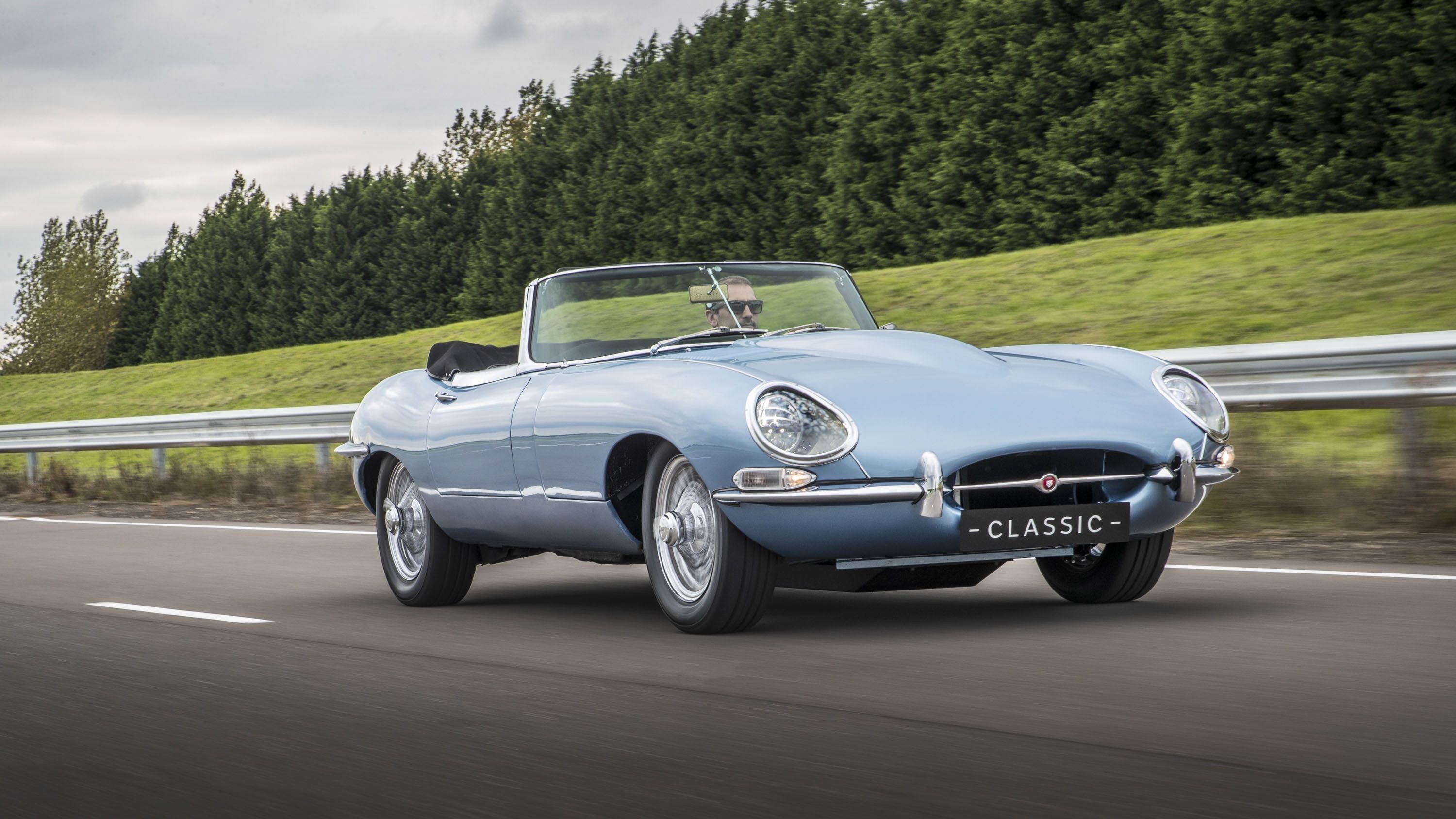 Blue 2017 Jaguar E-Type Zero driving on the road.