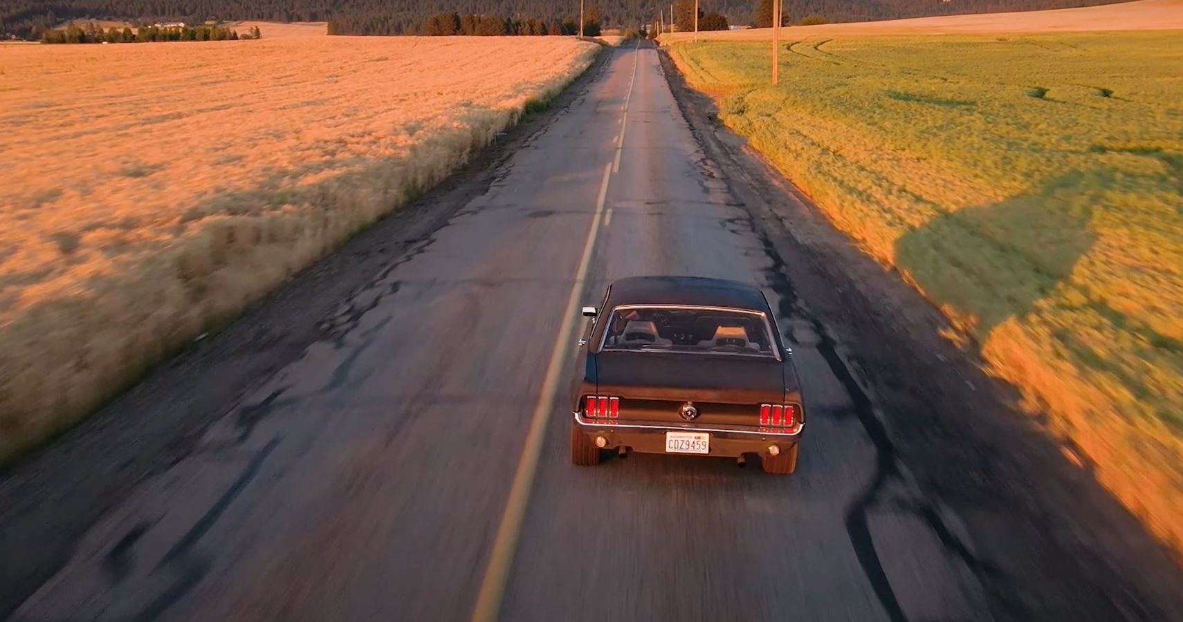 1967 Ford Mustang Rear on road at distance, black, sunset