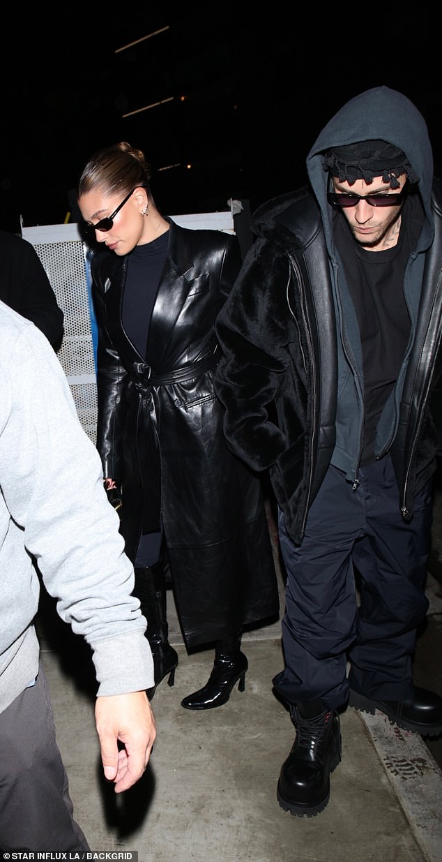 New mom Hailey wore a black leather trench coat with a navy dress - with her locks slicked back into a bun